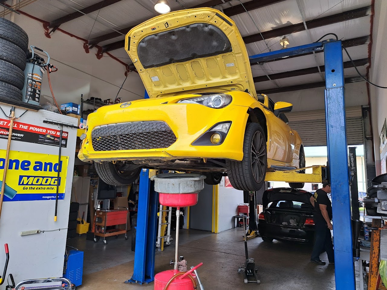 A clean, organized professional auto shop interior with a classic car on a lift